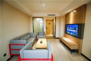 - un salon avec un canapé et une télévision dans l'établissement Thank Inn Chain Hotel Shangqiu Yongcheng Jinbo Grand Plaza, à Yongcheng