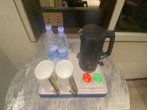 a table with a blender and two bottles and spoons at LanOu Hotel Suqian Central Shopping Mall in Suqian