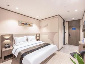 a bedroom with a large white bed in it at LanOu Hotel Langfang Gu'an Daxing Airport Wildlife Park in Langfang