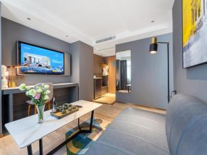 ein Wohnzimmer mit einem Tisch und einem TV in der Unterkunft LanOu Hotel Shenzhen Luohu Ruipeng Building in Shenzhen