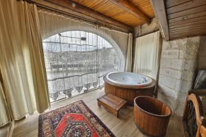um quarto com uma banheira e uma grande janela em Divan Cave House em Goreme