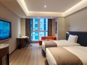 Habitación de hotel con 2 camas, escritorio y TV. en LanOu Hotel Lianyungang Donghai High-speed Railway Station Crystal City, en Donghai
