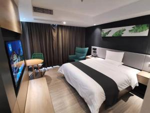 een slaapkamer met een bed, een bureau en een televisie bij Thank Inn Chain Heyuan Zijin Baocheng Commercial Plaza in Zijin