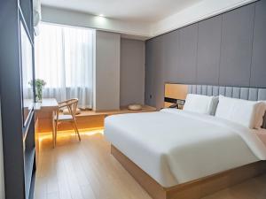 a bedroom with a large white bed and a table at Thank Inn Chain Kashgar Ancient City Wanda in Kashgar