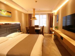 een hotelkamer met een groot bed en een bureau met een televisie bij LanOu Hotel Impressions of Taipei Xiantao City in Xiantao