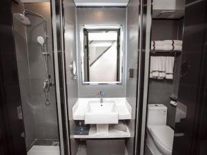 a small bathroom with a sink and a shower at Thank Inn Chain Hami Queen Sky Street in Qumul