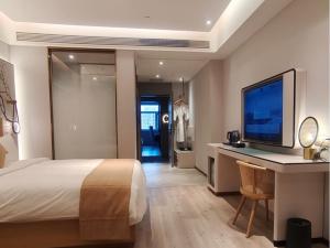 a bedroom with a bed and a desk with a television at LanOu Hotel Lianyungang Donghai High-speed Railway Station Crystal City in Donghai