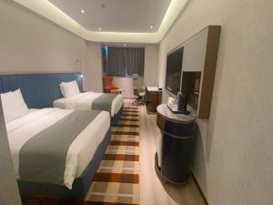 a hotel room with two beds and a television at LanOu Hotel Suqian Central Shopping Mall in Suqian