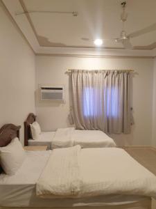 a bedroom with three beds and a window at شقق مأوى الدانة للشقق المخدومة in Ţubarjal