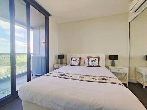 a white bedroom with a large bed and large windows at Green View 2B2B Olympic Park in Sydney
