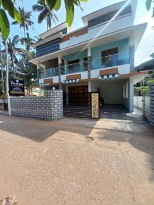 a building on the beach with palm trees at New PALM BAY RESIDENCY in Varkala