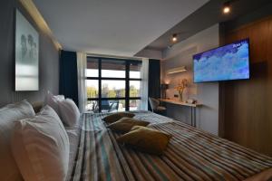um quarto com uma cama grande e uma televisão de ecrã plano em Boutique Hotel by BlackSeaRama em Balchik