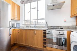 a kitchen with wooden cabinets and a sink at The Primrose Hill Flats in London