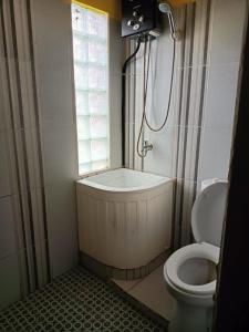 a bathroom with a shower and a toilet and a window at OYO 91232 Hotel Garuda in Sumenep