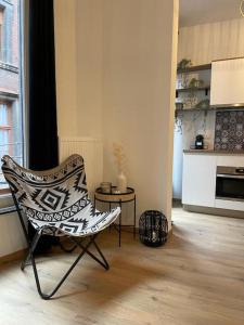 a living room with a chair and a kitchen at Suite 26-Appartement au coeur de Namur in Namur