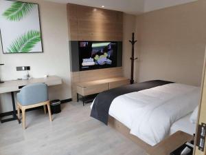 Yongcheng的住宿－尚客优品商丘永城金博大广场酒店，一间卧室配有一张床、一张书桌和一台电视。