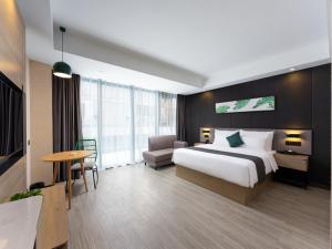 una camera d'albergo con un grande letto e un tavolo di Thank Inn Chain Hami Queen Sky Street a Hami