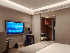 a hotel room with a bed and a flat screen tv at LanOu Hotel Lianyungang Donghai High-speed Railway Station Crystal City in Donghai