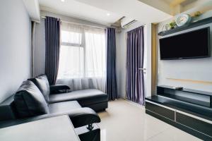 a living room with a couch and a flat screen tv at OYO Life 91614 Jarrdin Apartment By Hallo Tidur by Ozi in Bandung