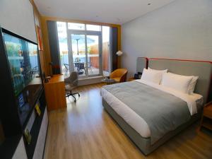 a bedroom with a large bed and a living room at LanOu M Hotel Shangxing Luxun's Hometown in Shaoxing