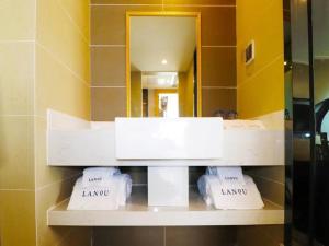 a shelf with three towels in front of a mirror at LanOu Hotel Xilinhot China Madu Cultural Plaza in Xilinhot