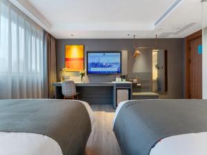 a bedroom with a desk with a tv on the wall at LanOu Hotel Shenzhen Luohu Ruipeng Building in Shenzhen
