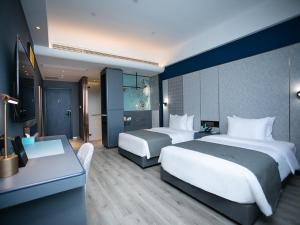 LianshuiにあるLanOu Hotel Huai'an Lianshui High-Speed Railway Station Yanhuang Avenueのベッド2台とデスクが備わるホテルルームです。