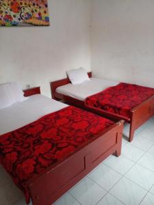duas camas num quarto com lençóis vermelhos em Hotel Raya em Plaosan