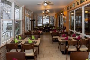 a restaurant with wooden tables and chairs and windows at Vizafogó Panzió és Étterem in Baja