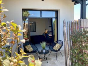 d'une terrasse avec quatre chaises et une table. dans l'établissement Hôtel particulier - Les lodges du Bassin d'Arcachon- Petit-déjeuner sur demande- Prestations haut de gamme, à Gujan-Mestras