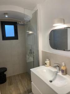 uma casa de banho com um lavatório e um chuveiro com um espelho. em Vicolo Rosso 2 em Dolceacqua