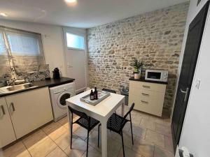 a kitchen with a table and two chairs and a microwave at Le Patio - Saint-Denis d’Oléron in Saint-Denis-dʼOléron