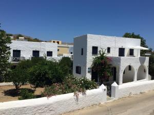 a white house with a white fence and flowers at Utopia Hotel Apartments in Agia Marina