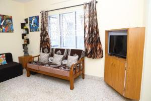 - un salon avec un canapé, une télévision et une fenêtre dans l'établissement Aakruti- centrally located home in malleswaram, à Bangalore