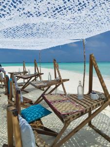 un grupo de mesas y sillas en la playa en Thari Fushi Luxury Maldivian Experience - All Inclusive, en Thinadhoo