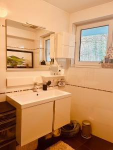 a white bathroom with a sink and a window at Hesp Guest House in Hesperange