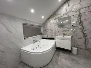 a bathroom with a large white tub and a sink at Хотел VIP APART HOUSE in Pleven