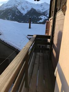 a wooden bench on a balcony with a snow covered mountain at Chalet del Sole in Quinto