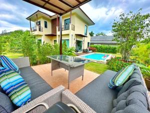 a patio with a couch and a table in front of a house at Krabi Aonang & Alpha villa in Ao Nam Mao
