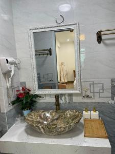 a bathroom with a stone sink and a mirror at Nhà Nghỉ Huyền Anh in Hanoi