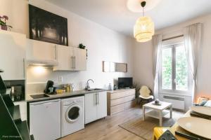 a kitchen with white cabinets and a washer at T1 Cocon prox. Gare/Métro, commerces, Lyon centre in Villeurbanne