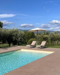 einen Pool mit 2 Stühlen, einem Tisch und einem Sonnenschirm in der Unterkunft All'Ombra Del Tiglio in Pistoia