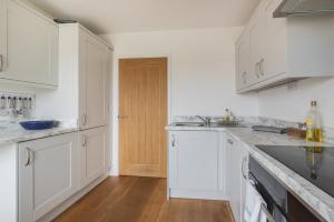 a white kitchen with white cabinets and a wooden door at Stylish 3 bedroom house with garage in Frome