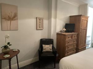 a bedroom with a bed and a chair and a dresser at Milton House Studio Apartments Askrigg in Askrigg