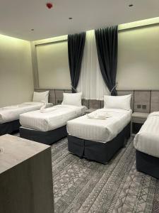 a hotel room with three beds in it at فندق سرايا الجوار - SARAYA ALJIWAR HOTEL in Makkah