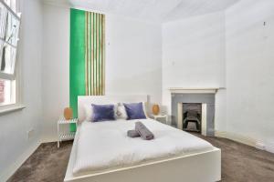 1 dormitorio con cama blanca y chimenea en Spacious 3 Bedroom House City Centre Millers Point 2 E-Bikes Included, en Sídney