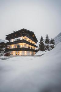 Un bâtiment dans la neige avec des lumières allumées dans l'établissement Apartmenthaus Maxl, à Bad Hofgastein