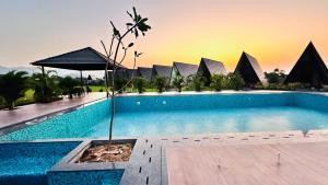 a swimming pool with a sunset in the background at Regenta Resort Vindhyachal, Statue of Unity in Kevadia