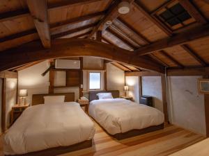 2 camas en una habitación con techos de madera en NIPPONIA HOTEL 伊賀上野 城下町, en Iga