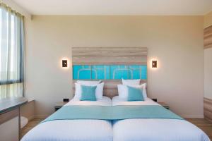 une chambre avec un grand lit avec des oreillers bleus et blancs dans l'établissement Best Western Plus Hôtel Escapade Senlis, à Senlis